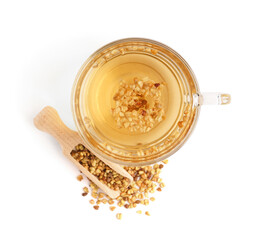 Glass cup of fresh buckwheat tea and wooden scoop on white background