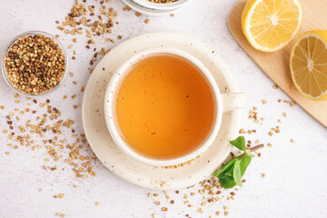 Cup of fresh buckwheat tea, lemon and mint on light background