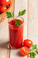 Fresh tomato juice on wooden rustic background. Organic vegetable drink with parsley.