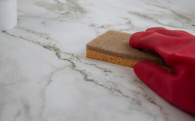 Hand with red glove holding an eco-friendly sponge for washing marble surface