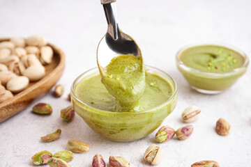 Tasty pistachio paste in bowls with spoon on white background