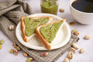 Plate and bread pieces with tasty pistachio paste on light background