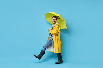 Young man with yellow umbrella on light blue background