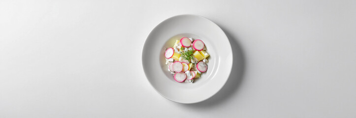 Cucumber and radish salad with fresh herbs, served in a white bowl for a healthy appetizer