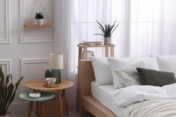 Stylish living room interior with bed, bedside tables, lamp and houseplants