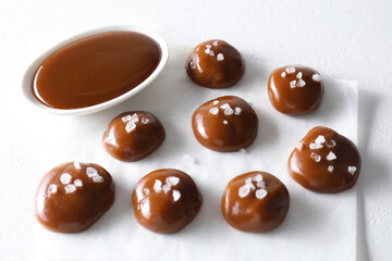 Tasty candies, caramel sauce and salt on white table