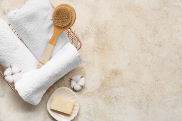 Clean soft towels, body massage brush and cotton flowers in metal box on grunge background