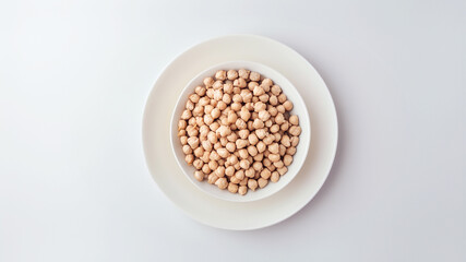 Bowl of dried chickpeas on a white plate, ready for cooking a nutritious and protein-rich meal