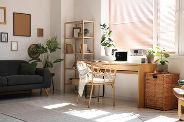 Light office with workplace, modern laptop, houseplants and armchair