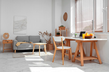Wicker basket with citruses and laptop on workplace in light room