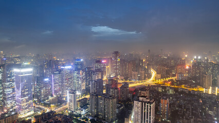 Vibrant Urban Skyline Illuminated at Night with Dramatic Clouds