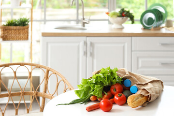 Vegetables, milk and bread in eco bag on table in kitchen