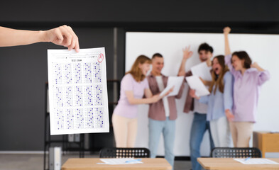 Female student with results of exam in classroom, closeup