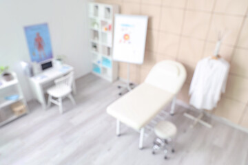 Blurred view of medical office with couch and doctor's workplace