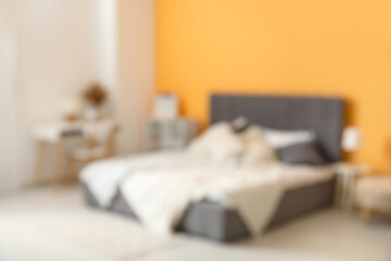 Modern bedroom with bed, bedside table and workplace, blurred view
