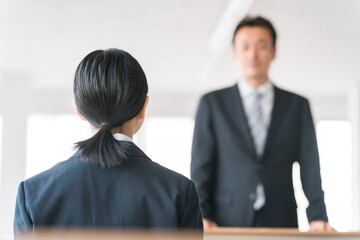 教室で授業を受ける制服を着た高校生・中学生の後ろ姿と先生（補習）
