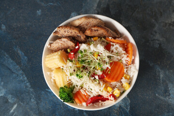 Bowl of tasty rice with chicken and vegetables on color background