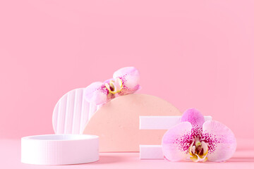 Decorative podiums with beautiful orchid flowers on pink background