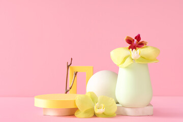Decorative podiums with beautiful orchid flowers and tree branch on pink background