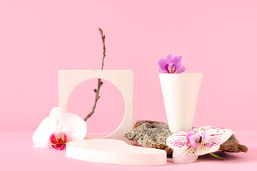 Decorative podiums and tree bark with beautiful orchid flowers on pink background