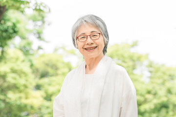 新緑の公園にいる笑顔のシニア女性
