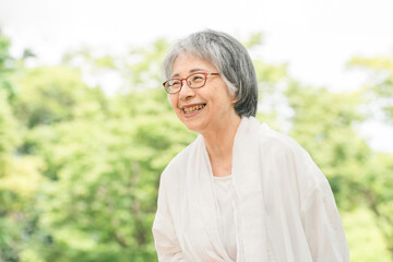 新緑の公園にいる笑顔のシニア女性

