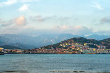 Fototapeta premium Scenic Coastal View with Mountains and Cityscape at Sunset