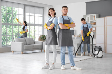 Group of young janitors cleaning in room