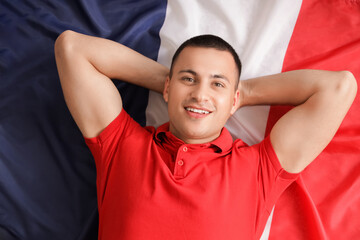 Young man lying on flag of France, top view