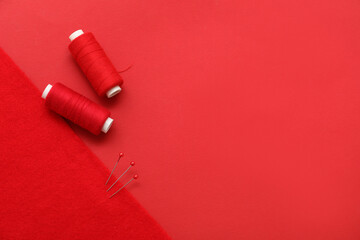 Sewing thread spools, ball pins and felt on red background