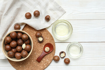 Composition with macadamia oil and nuts on light wooden background