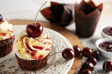 Plate with sweet cherry cupcakes and bowls of jam on white background