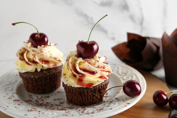 Plate with sweet cherry cupcakes and berries on white background