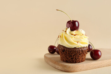Wooden board with sweet cherry cupcake and berries on beige background