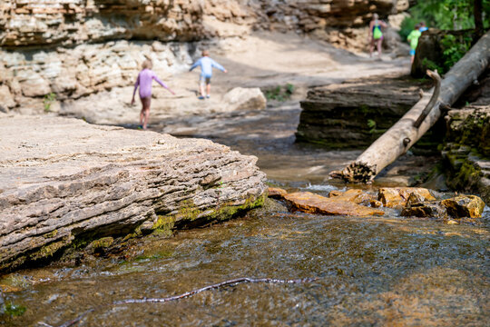 Selective focus on eroded Rock creek with defocused children on the trail to the Devils Bathtub waterfall in Spearfish Canyon, South Dakota