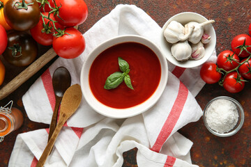 Bowl of fresh tomato soup with fresh vegetables and garlic on dark background