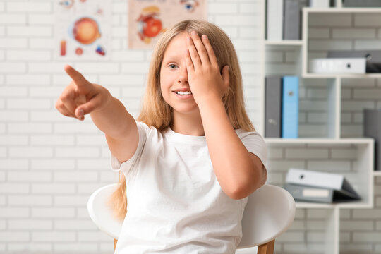 Teenage girl checking her eyesight at ophthalmologist's office. Children's Eye Health and Safety Awareness Month