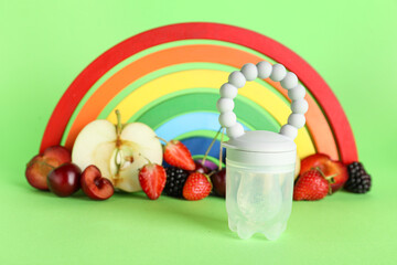 Composition with baby nibbler, ripe fruits and toy on color background