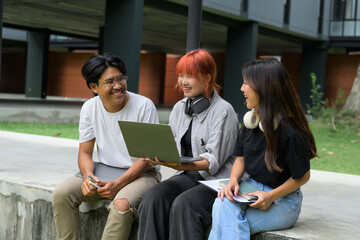 Group of Diverse Students Studying Together Outdoors with Laptops and Notebooks at Modern Campus