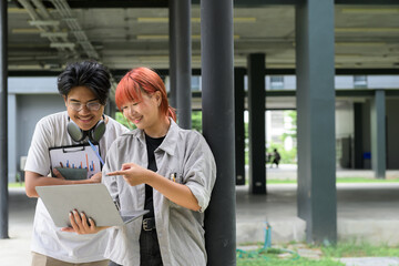 Obraz premium Two Students Collaborating on a Project with a Laptop in a Modern Campus Setting