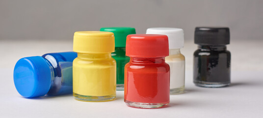 scattered colorful poster color bottles isolated white surface, mock-up template without label, bright paints for artwork craft projects in selective focus