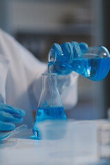 Group of dedicated scientist conduct chemical experiment in medical laboratory, carefully drop precise amount of liquid from pipette into test tube for vaccine drug or antibiotic development. Neoteric
