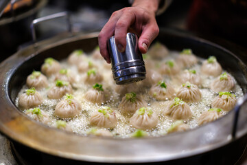 chef's hand cooking pour pepper on xiaolongbao streamed bun in kitchen