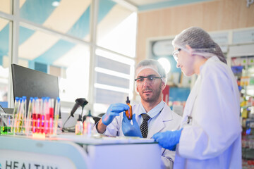 Obraz premium scientists perform experiments and record data. people arranges equipment with test tubes and chemicals for producing medicine and biochemistry. man hold tubes of chemical liquids and plant samples.