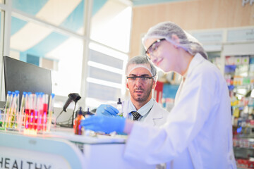 scientists perform experiments and record data. people arranges equipment with test tubes and chemicals for producing medicine and biochemistry. man hold tubes of chemical liquids and plant samples.