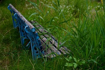 雑草が生えて座れなくなった公園の古いベンチ