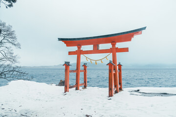 Red Japanese Torii gate of Goza no Ishi Shrine at lake tazawa in winter, located in Semboku city, Akita Prefecture, northern Japan. Landmark and famous for tourists attractions in Tohoku region, Japan