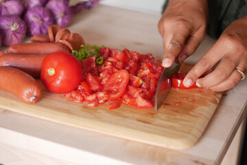 cutting fresh tomato on a chopping board at kitchen 