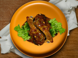 Butter fried chicken with lettuce served on a yellow plate. A famous chinese food that has sweet and savory taste.