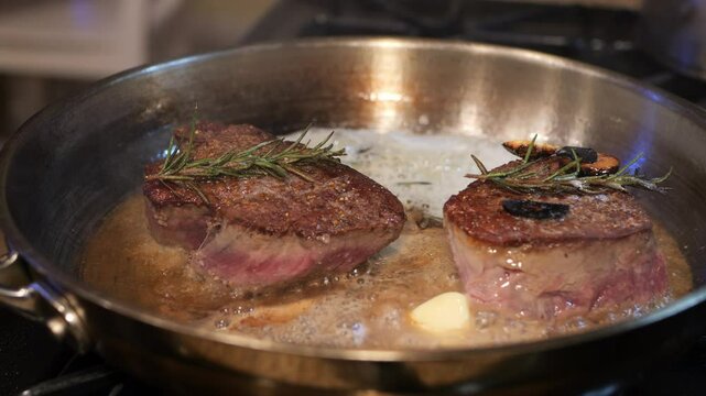 Filet mignon searing in butter with herbs 